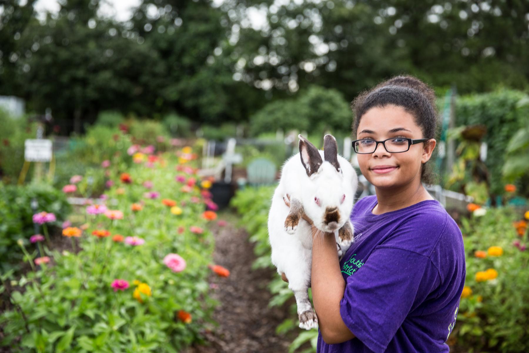 teen girl smiling while holding rabbit.