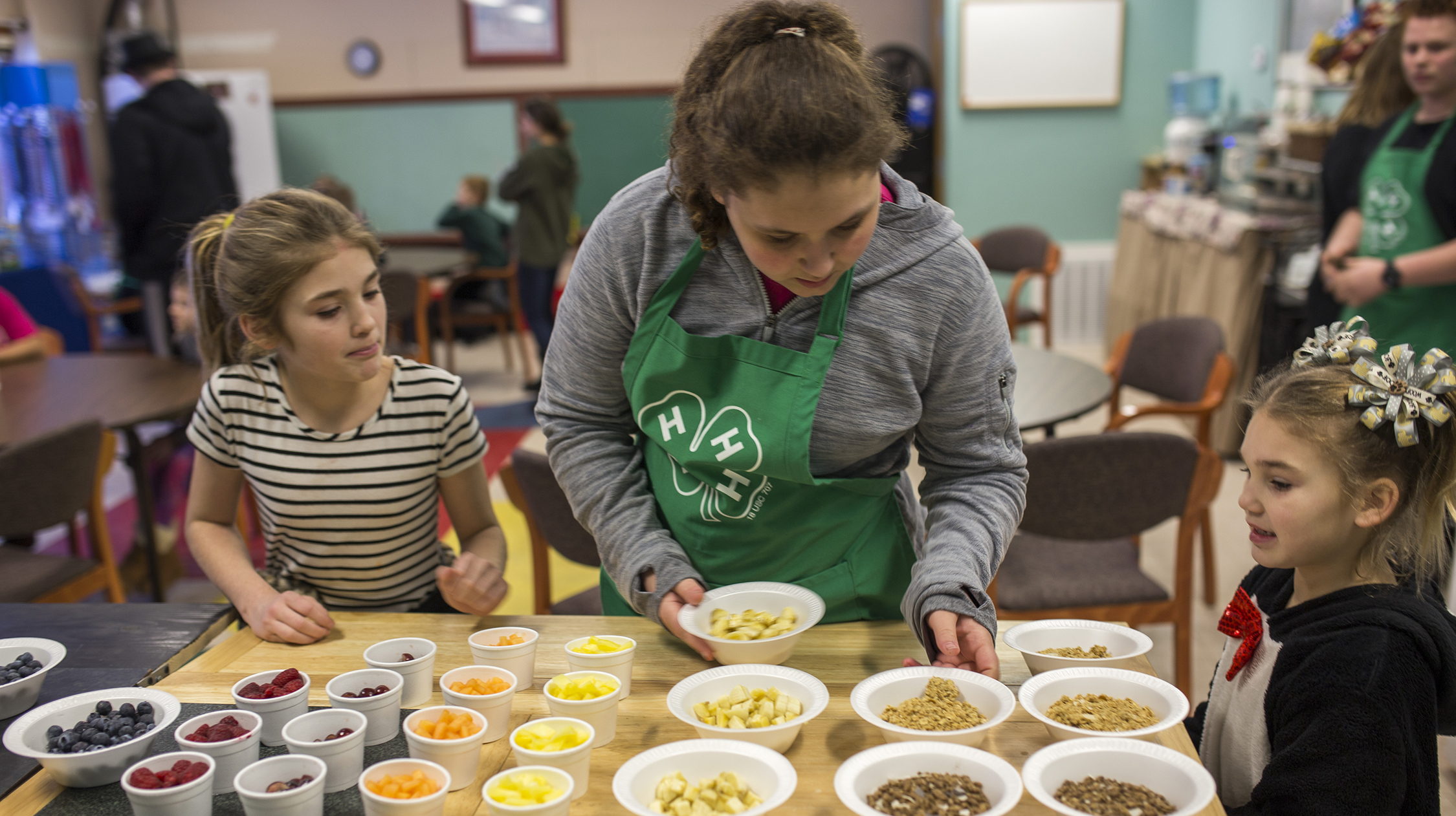 adult helps young children dish out food