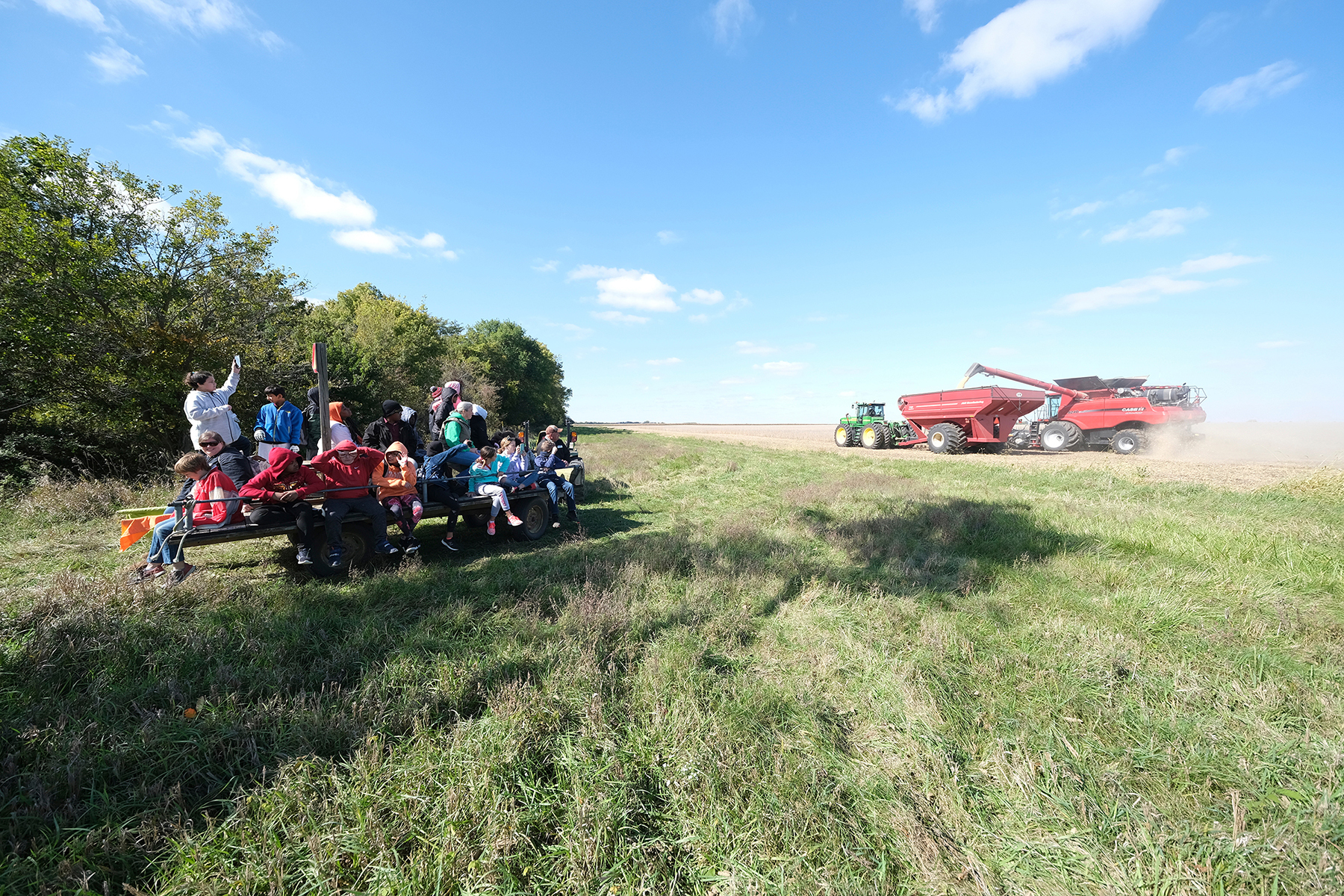 students watch as tractor drives across field
