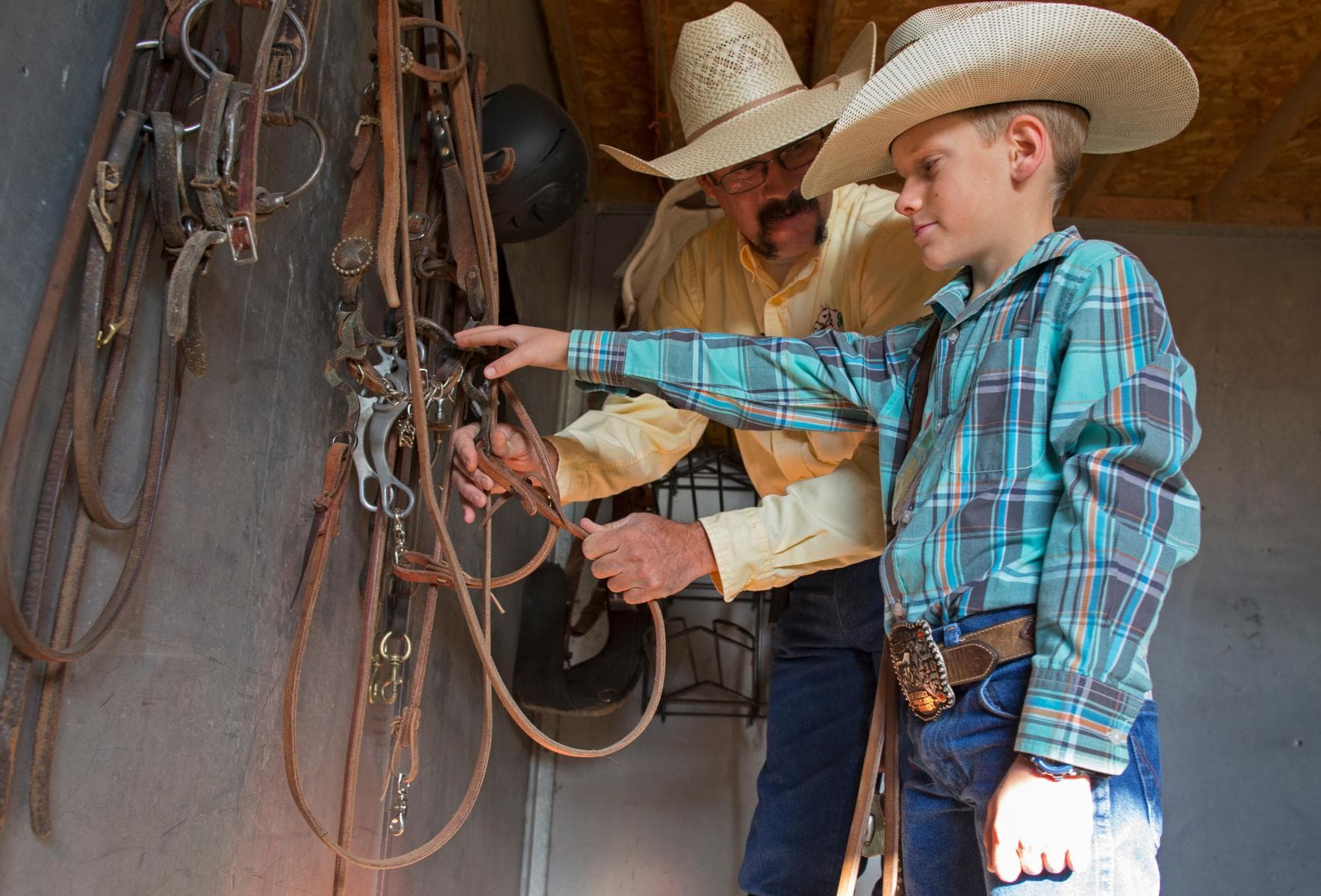 Adult helping youth select a horse bridle