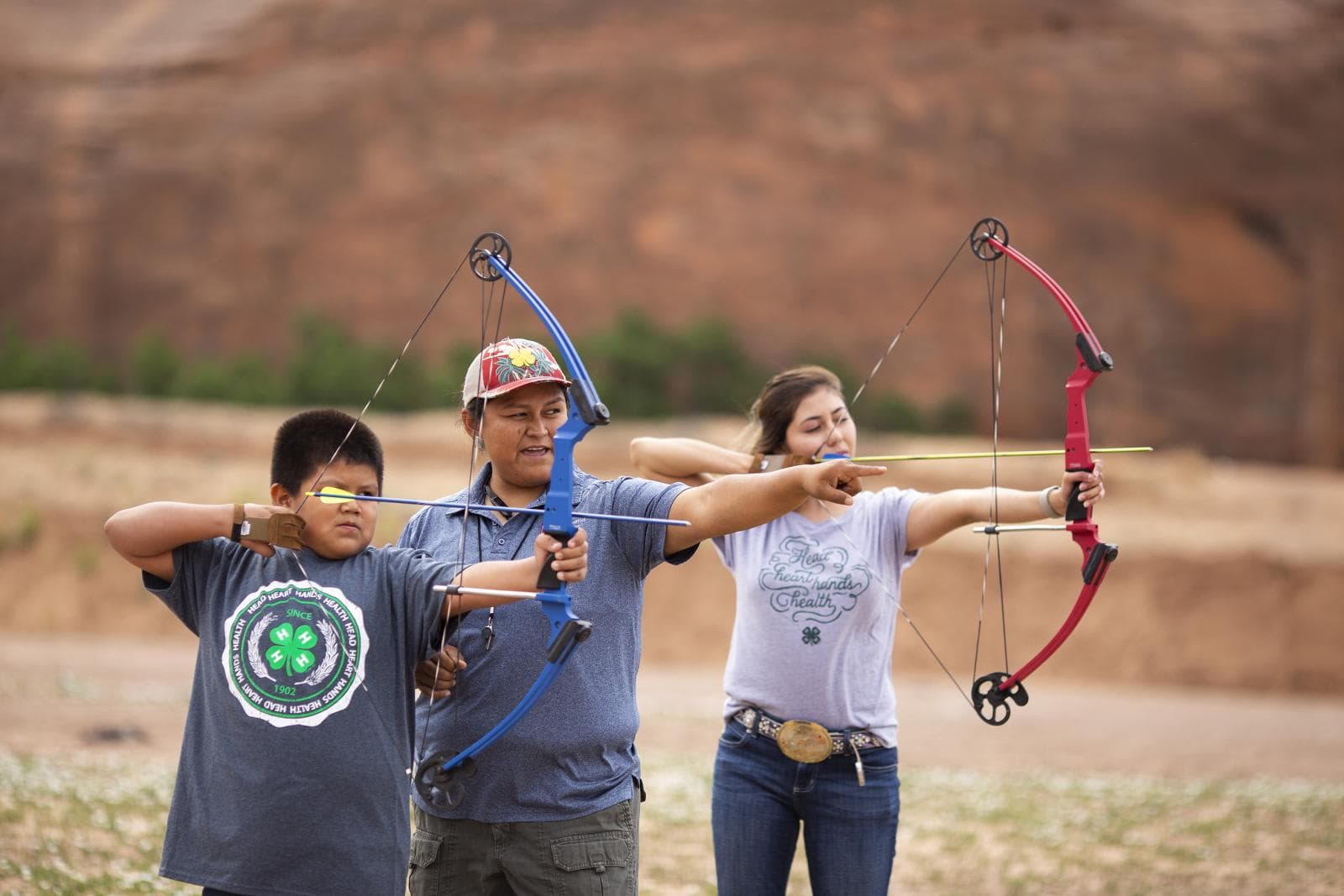 Adult helping youth in archery shooting sports project.