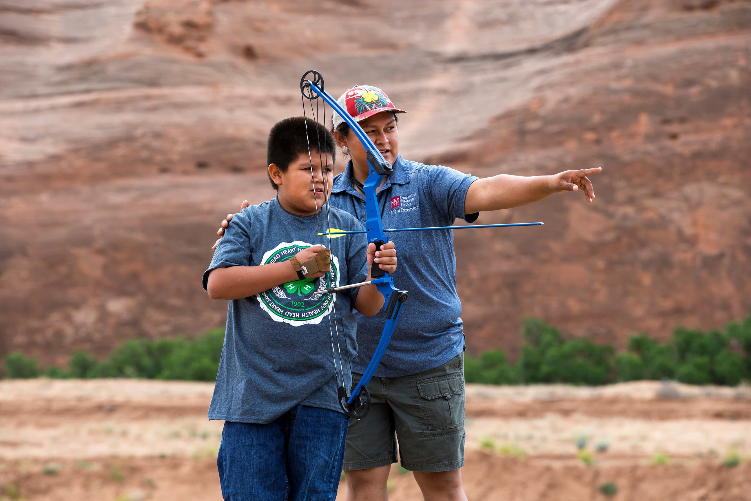 Adult helping youth in archery shooting sports project.