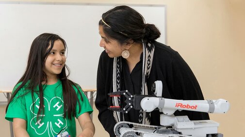Adult helping youth with STEM robotics project. 