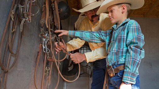 Adult helping youth select a horse bridle