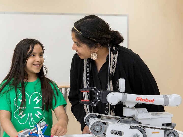 Adult helping youth with STEM robotics project. 