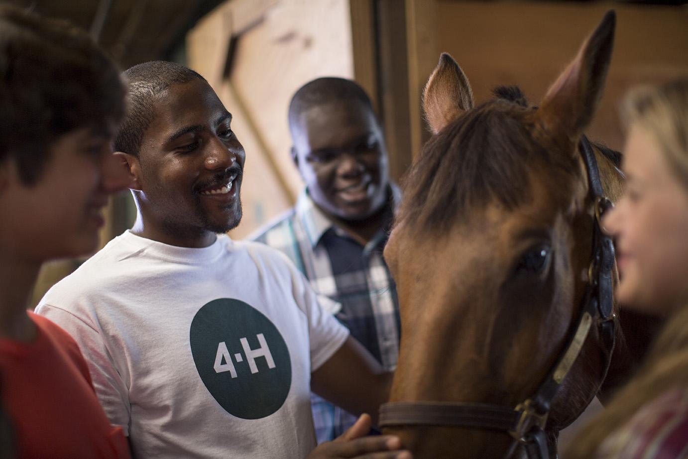 teens smiling and standing around a horse