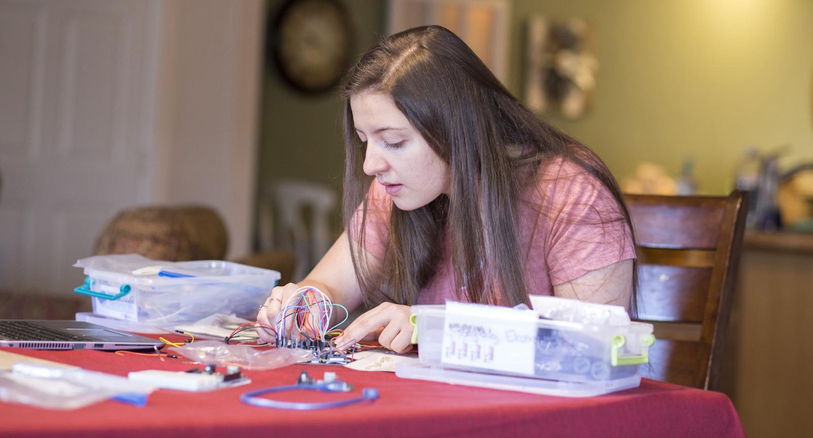 teen sits at kitchen table working on robotics project