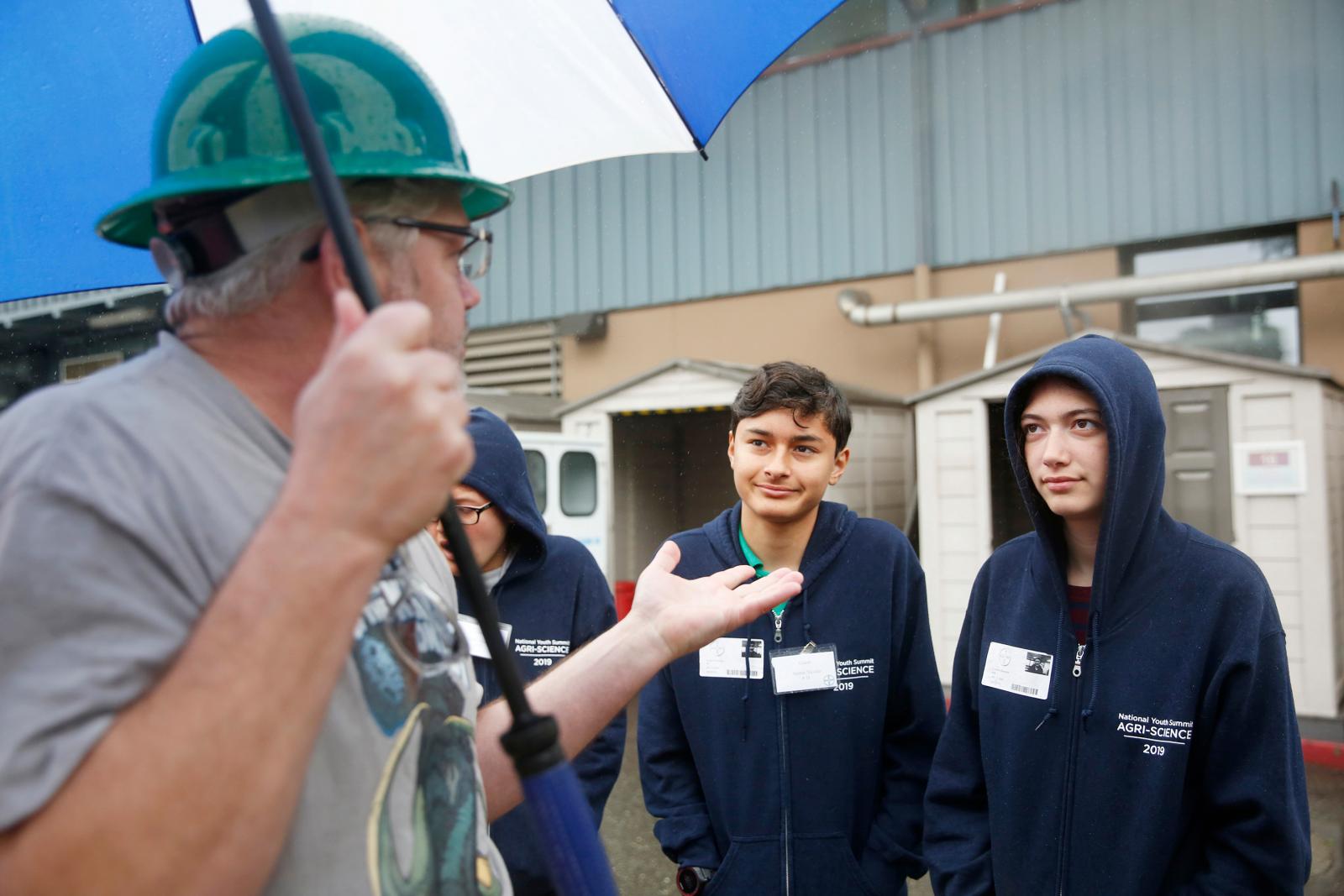 teens listening to adult wearing a hard hat