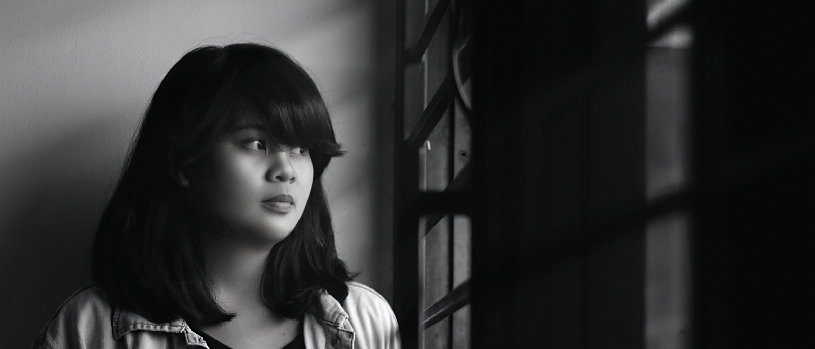 black and white photo of teen girl staring out a window