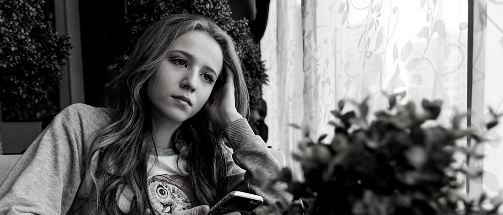 black and white photos of teen girl holding a phone but staring off into space