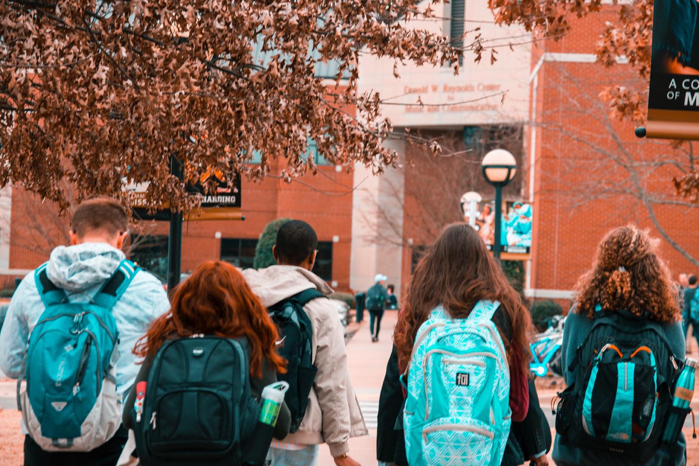 students wearing backpacks walking across campus