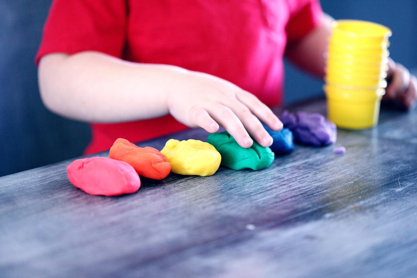 young child organizes balls of playdough by color